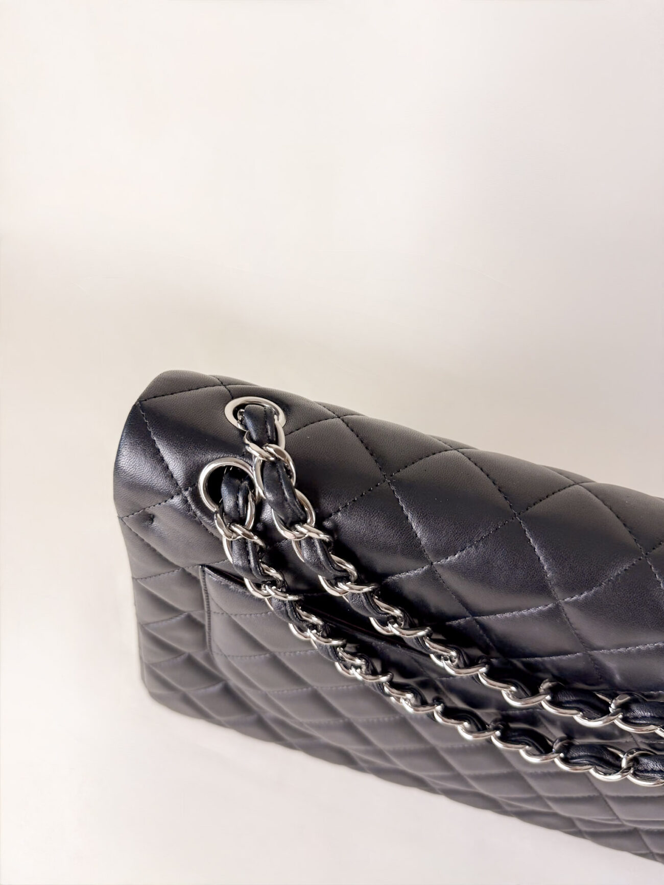 Top view of Chanel Classic Flap Maxi Jumbo Double Flap bag with chain in black lambskin and palladium hardware