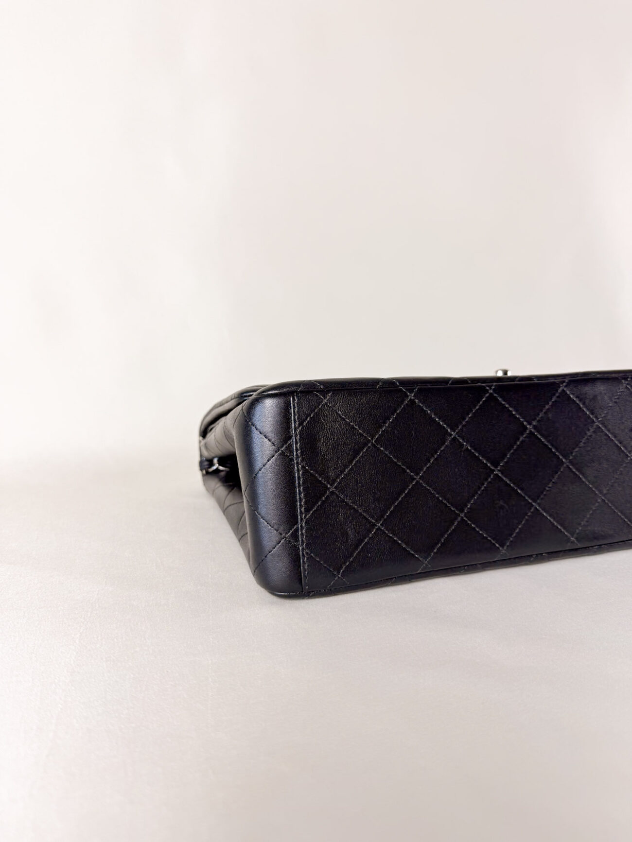 Left corner detail of Chanel Classic Flap Maxi Jumbo Double Flap bag in black lambskin