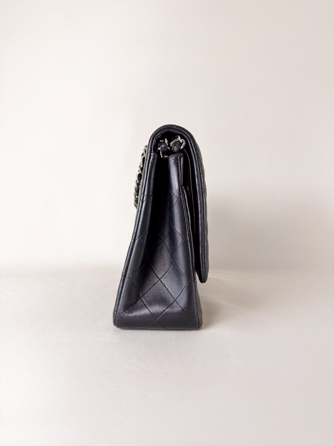Side view of Chanel Classic Flap Maxi Jumbo Double Flap bag in black lambskin with palladium hardware
