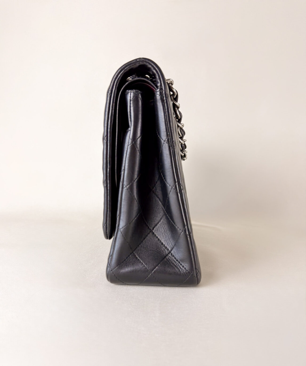 Opposite side view of Chanel Classic Flap Maxi Jumbo Double Flap bag in black lambskin with palladium hardware