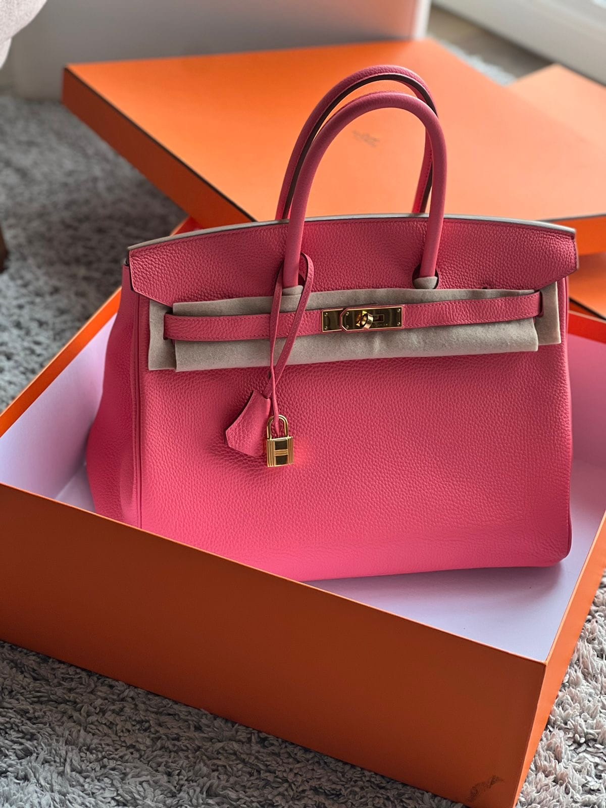 Hermès Birkin 35 Rose Azalée pink leather handbag with gold-tone hardware, padlock and protective felt, displayed in an orange Hermès box.