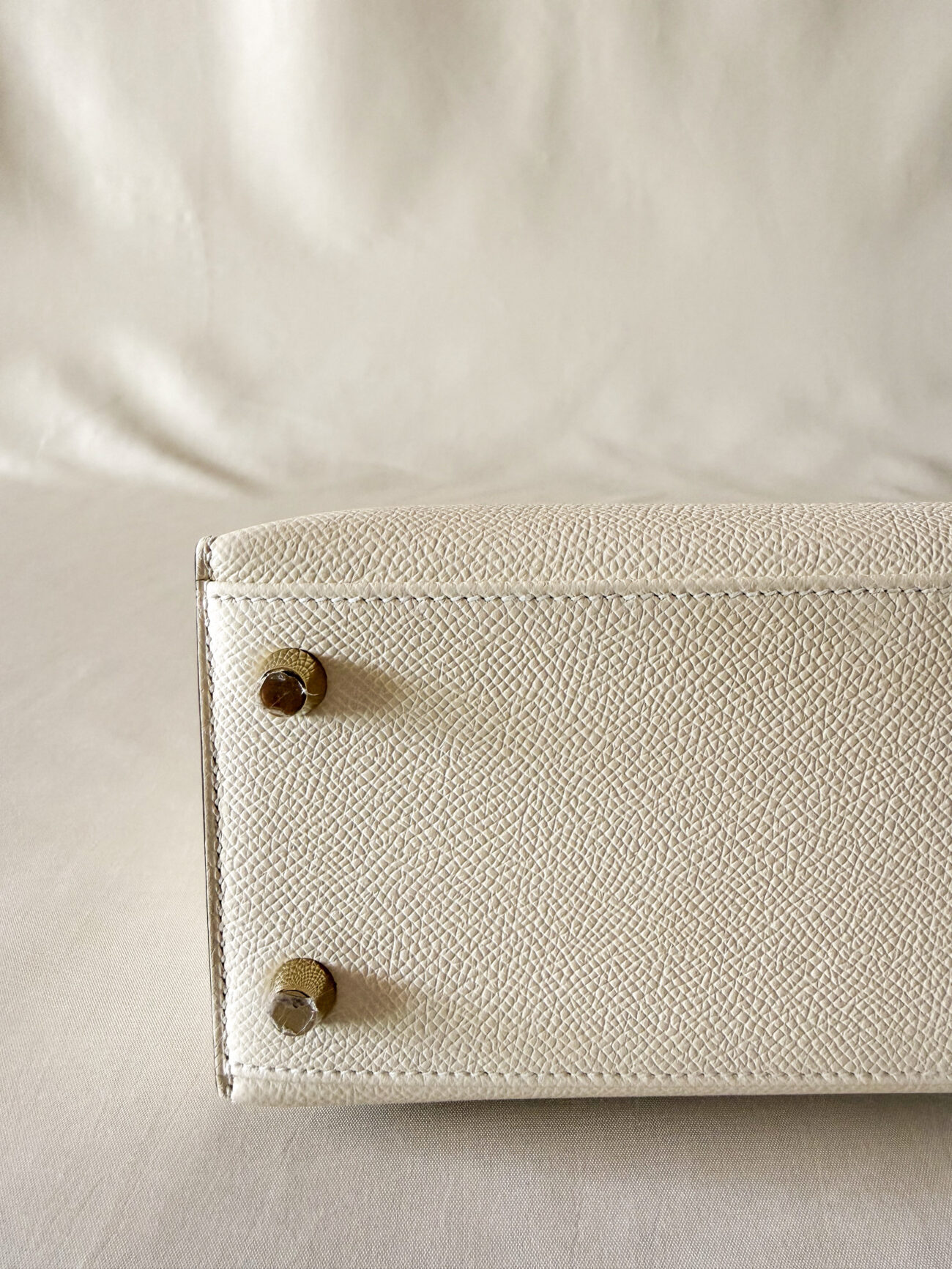 Hermès Kelly 25 epsom sellier in nata with gold hardware feet detail with protective stickers