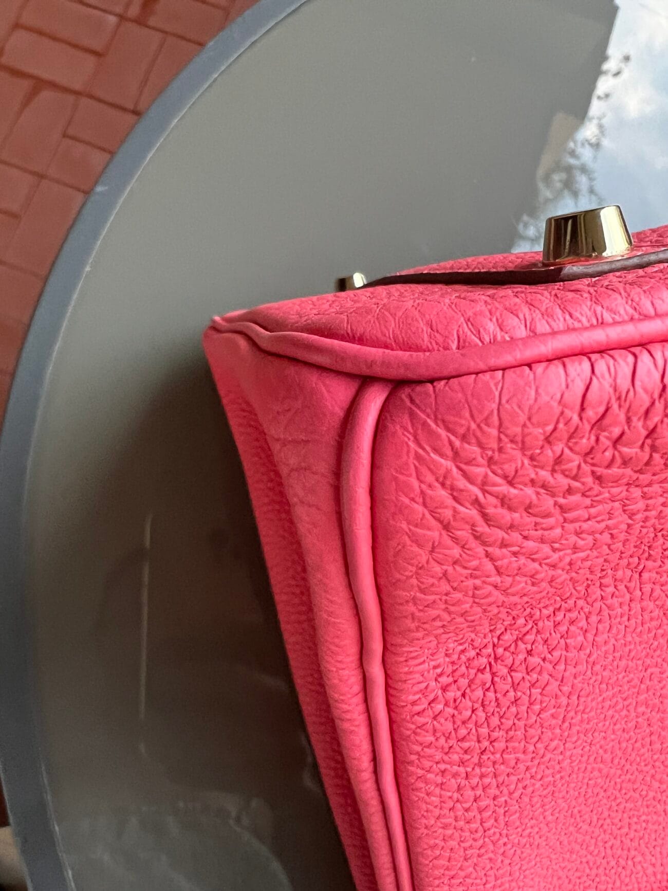 Close-up of the Hermès Birkin 35 Rose Azalée bottom corner showing pink grained leather, and gold-tone metal foot.