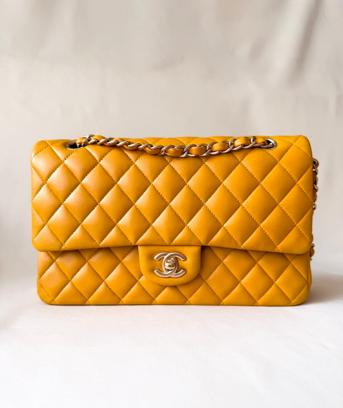 Chanel Classic Flap Medium mustard yellow lambskin bag with champagne hardware close-up front view