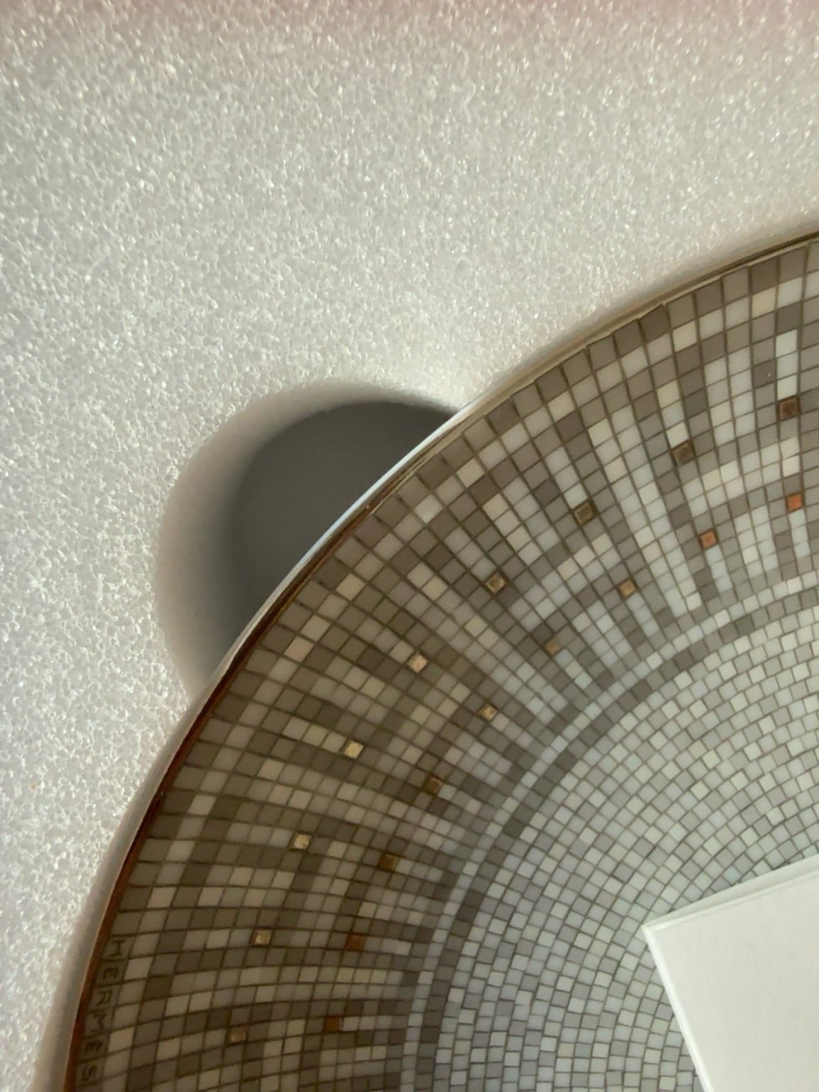 Close-up of authentic Hermès Mosaique au 24 Platinum foam insert with precise finger opening beside the plate