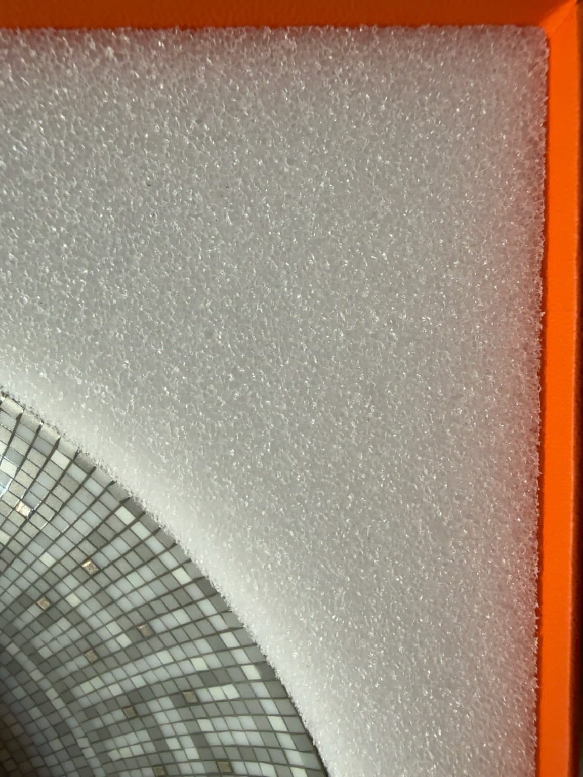 Close-up of authentic Hermès Mosaique au 24 Platinum white protective foam with fine dense texture.