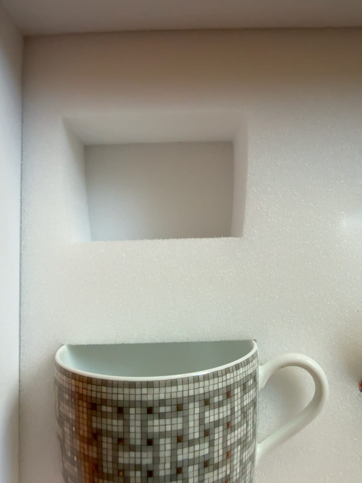 Authentic Hermès saucer perfectly fitted into a custom-cut white foam insert.