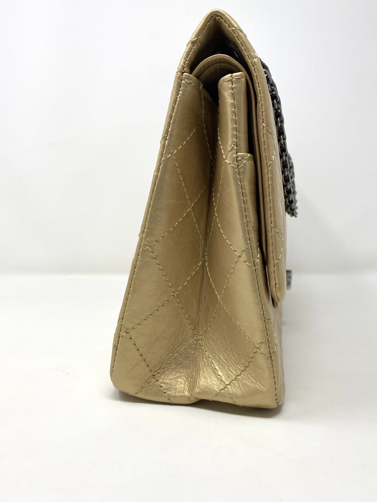 Chanel 2.55 Reissue gold aged calfskin quilted flap bag, side profile showing structured gusset and leather stitching.