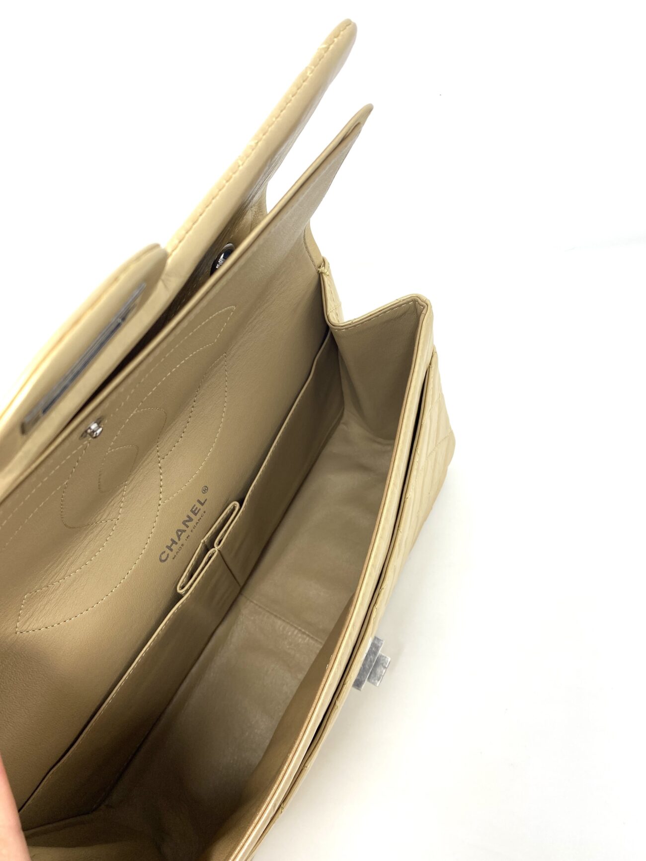 Chanel 2.55 Reissue gold leather double flap bag opened to reveal the stitched CC logo, inner compartments and Mademoiselle lock hardware.