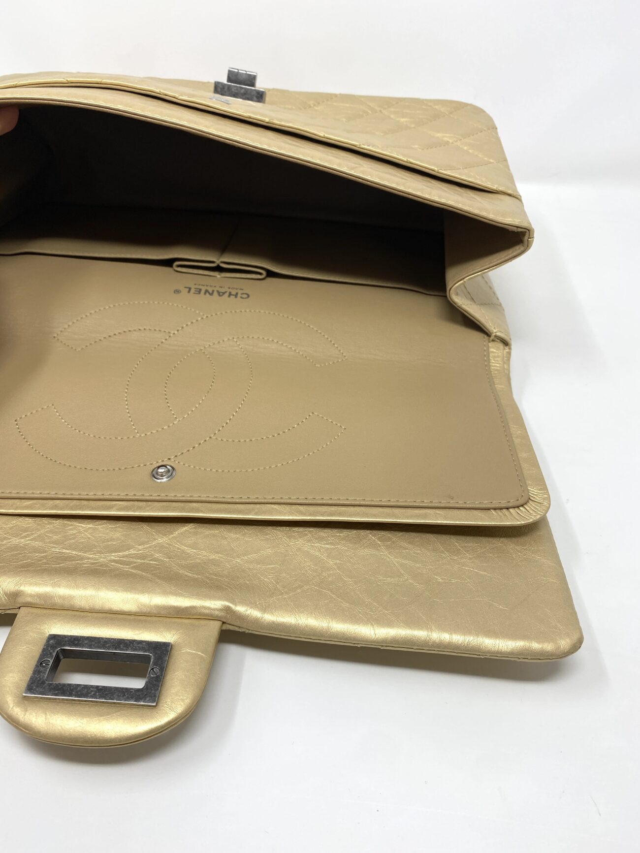 Chanel 2.55 Reissue gold aged calfskin bag showing open main compartment, leather lining, interior pockets and double flap construction.