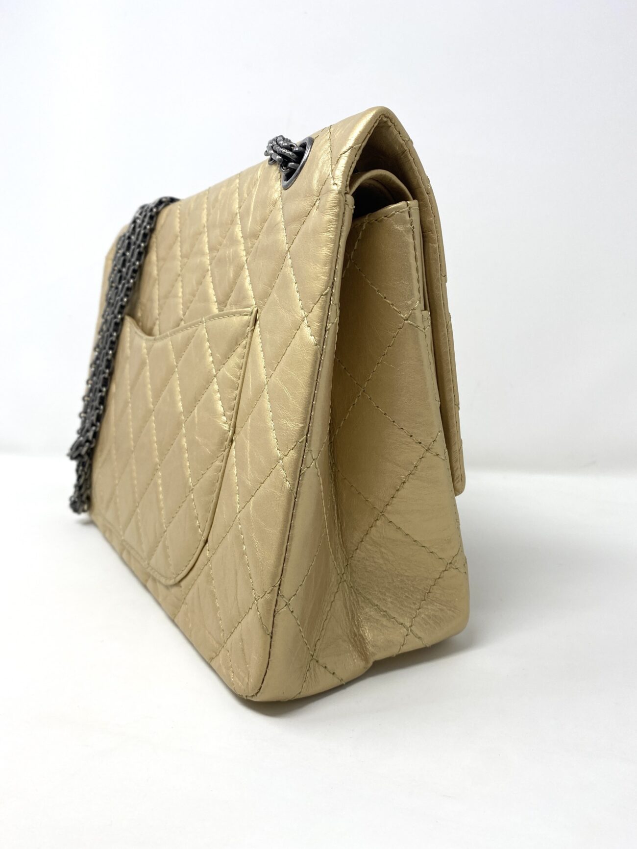 Chanel 2.55 Reissue gold aged calfskin flap bag viewed from the rear side, showing quilted leather, back pocket and side construction.